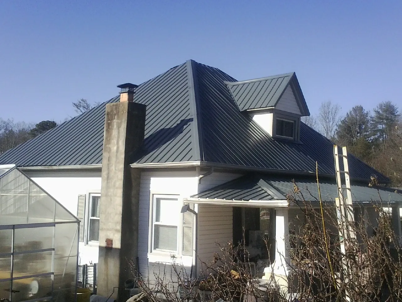 Dark blue standing seam metal roof on a white farmhouse with dormer — Slate & Tile Roof Repair by Roofing Brothers in Elmer