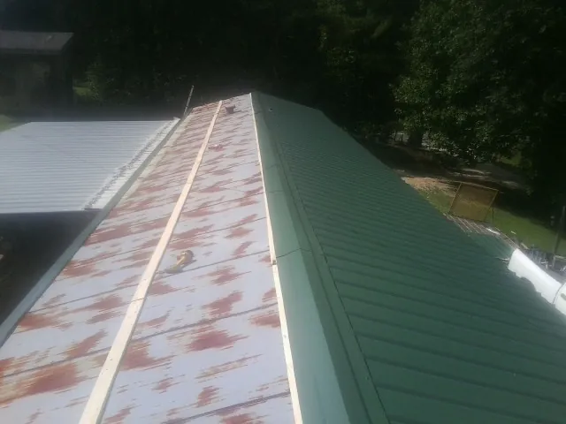 Old rusted panels beside newly installed green metal roofing — Wind Damage Roof Repair by Roofing Brothers in Elmer