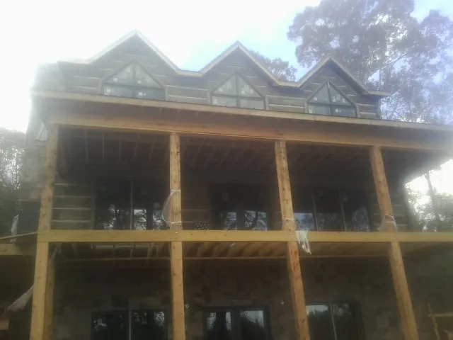 Dormers and porch framing on a large log home under construction — Roof Coating work by our crew in Elmer