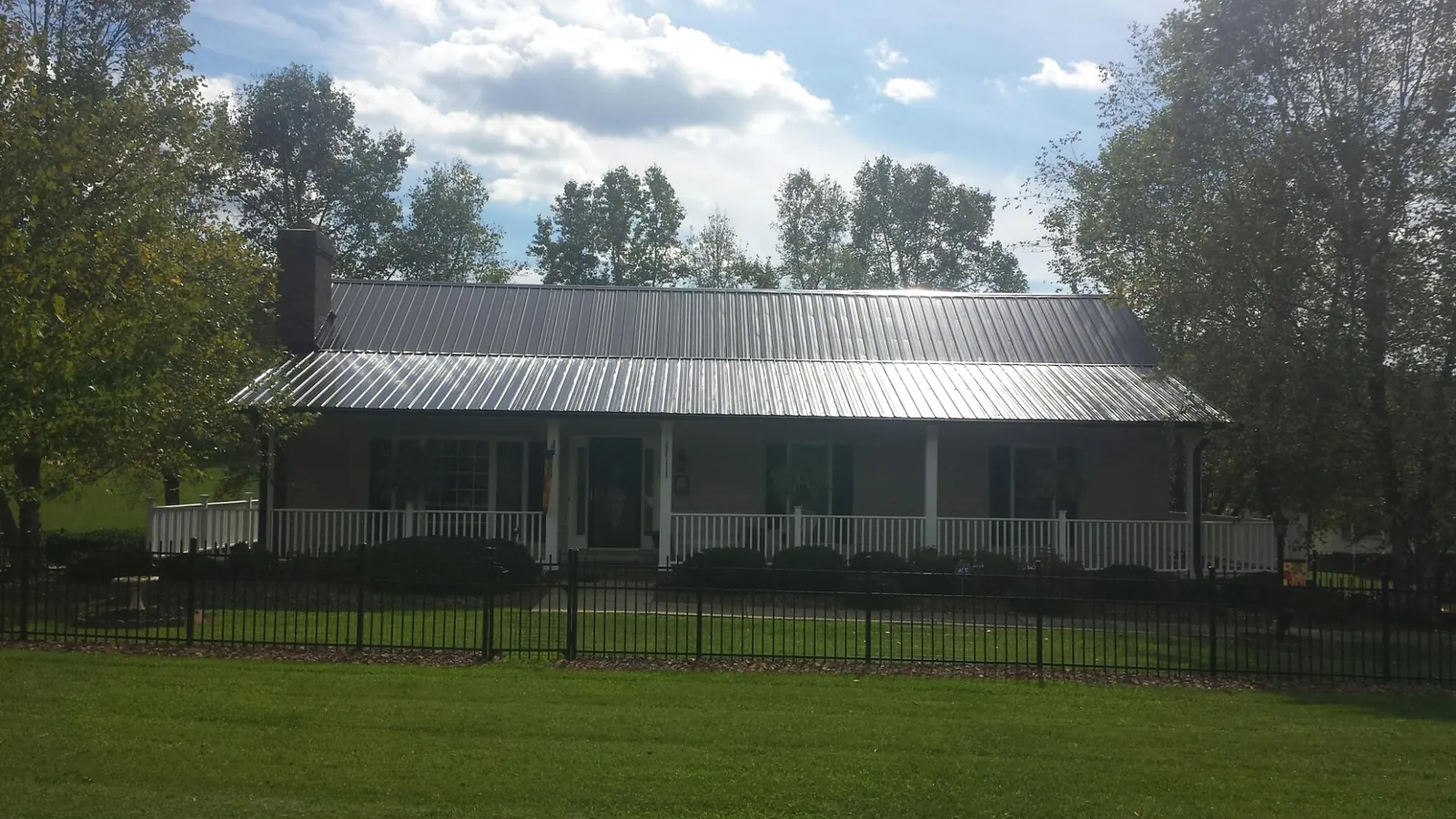 Gray metal roof on a brick ranch with a full width front porch — Gutter Guard Installation work by our crew in Elmer