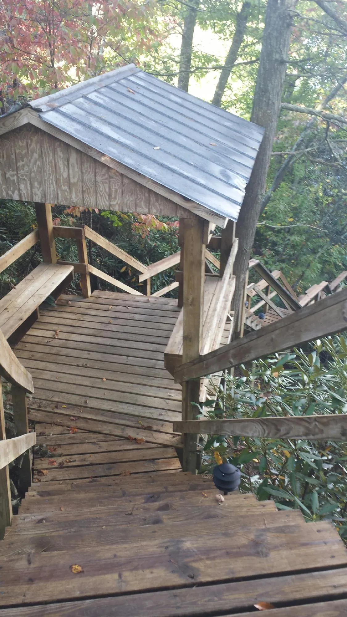 Metal roofed shelter over wooden steps on a wooded walkway — Skylight Repair & Installation work by our crew in Elmer