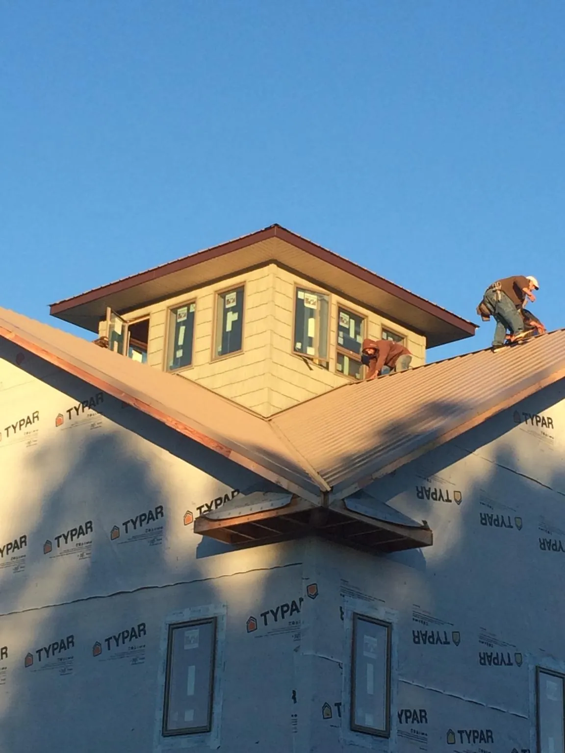 Roofers working around a rooftop cupola on a new metal roof at sunset — Roof Waterproofing in Elmer by Roofing Brothers